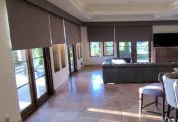 Somfy motorized blackout roller shades fully closed on large living room windows and glass doors in Agoura Hills, providing complete privacy and light blocking.