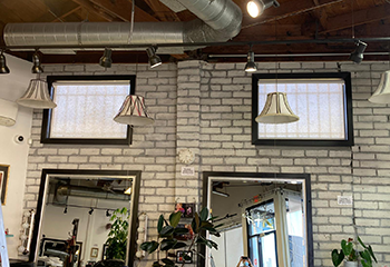 Interior of a salon undergoing renovation, with sheer roller shades being installed on expansive windows.